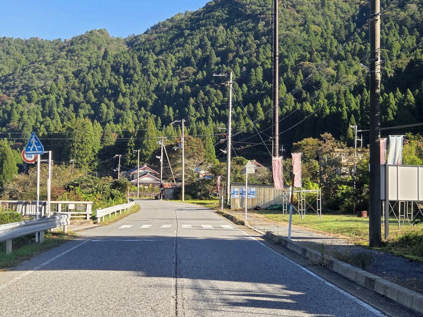 のぼり旗が立つ県道の先に、橋の入口が見える